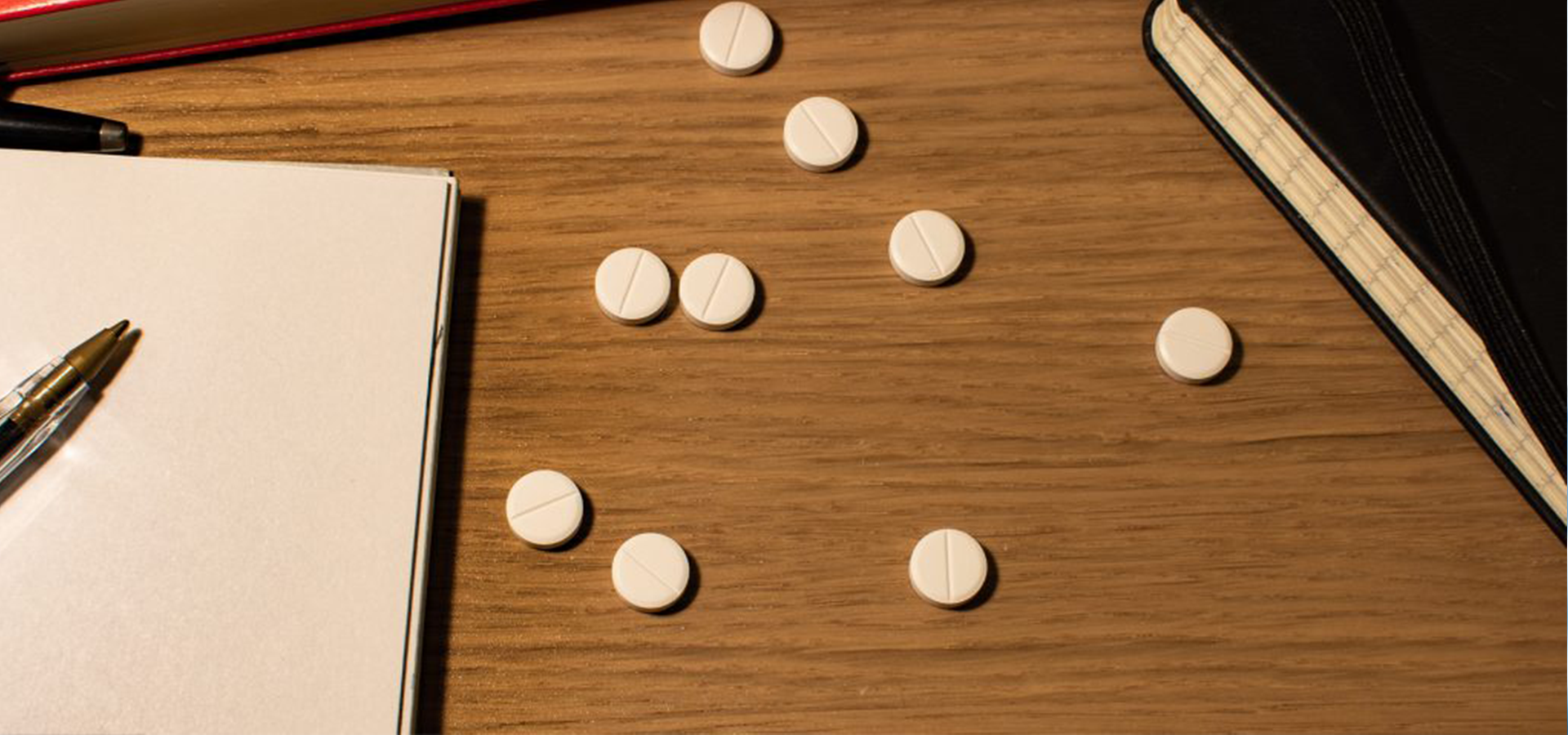 pills on a desk make people think about college students and substance abuse