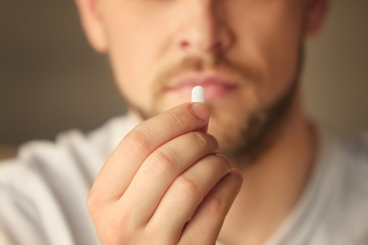 man holding a pill and debating the myths about drugs