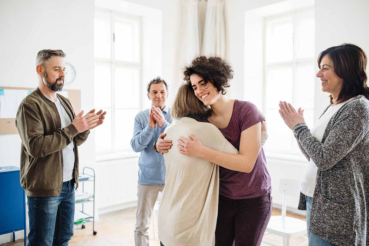 a group of people clap as they discuss the benefits of sober living homes